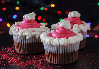 Three Christmas homemade chocolate cupcake with pink cream cheese frosting. Blur light and dark background.