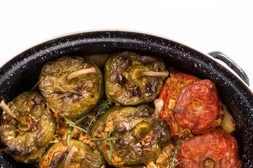 Stuffed green bell peepers and tomatoes in dish, on white background.