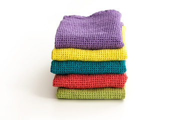 Stack of neatly folded colorful kitchen towels, on white background.