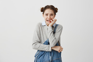 Woman in jeans jumpsuit biting her nails feeling fear looking on camera in stress. Female business beginner going through troubles worrying about her failure. Human emotions