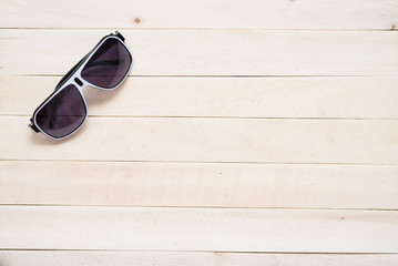 Sunglasses on light wooden table. Summer vacation concept. Place for text.