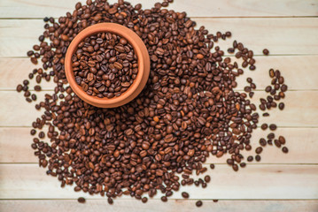 Clay pot filled with coffee beans on wooden table. Menu design. Place for text. Top view.