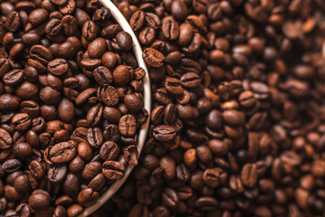 Porcelain cup filled with coffee beans close up on coffee beans background. Beverages menu design. Place for text. Top view.