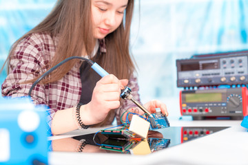 Schoolgirl in laboratory robots debug microcontroller