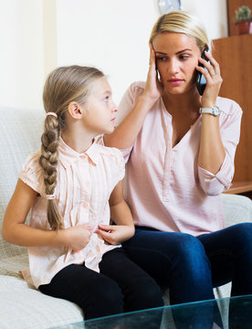 Worried mother calling doctor for daughter with abdominal pains