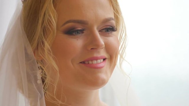 Pretty bride looking out of window and smiling on her wedding day