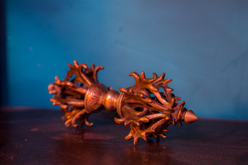 Tibetan Buddhist Dorje vajra ceremonial item on wooden table on blue background 