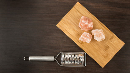 Himalayan salt with grater. Pink Himalayan salt with grinder on wooden background. Metal silver grater and red salt.