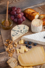 Tasting cheese dish on a wooden plate. Food for wine and romantic, cheese delicatessen on a wooden rustic table. Top view