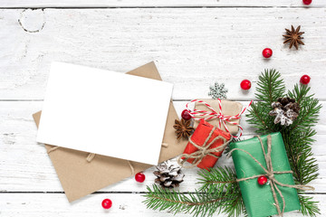 christmas blank greeting card and envelope with fir tree branches, red berries, pine cones and gift boxes