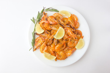 Fried prawns on a white plate. Shrimp fried in oil with garlic and lemon on a plate.