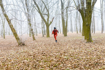 Young man running in forest on a cold winter day.