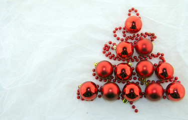 Christmas tree made of red pearls and shiny red balls on a white background