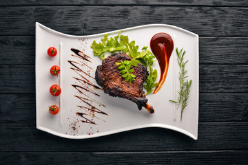 Steak on a bone with tomatoes and a hazelnut. Steak Fiorentino. On a wooden background. Free space for your text. Top view.