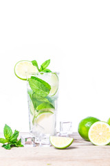 Mojito cocktail with fresh lime, mint leaves and ice cubes in a transparent glass on a wooden background. Refreshing alcohol drink. Isolated on white background.