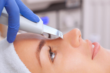 The doctor-cosmetologist makes the apparatus a procedure of ultrasound cleaning of the facial skin...