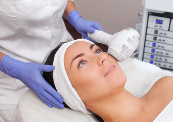 The cosmetologist makes the procedure Cryotherapy of the facial skin of a beautiful, young woman in a beauty salon.Cosmetology and professional skin care.