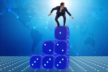 Businessman balancing on top of dice stack in uncertainty concep