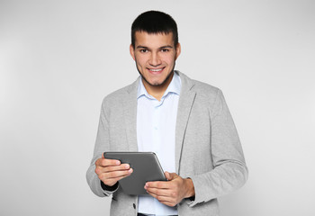 Male manager with tablet computer on grey background