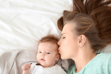 Young mother and cute baby on bed at home