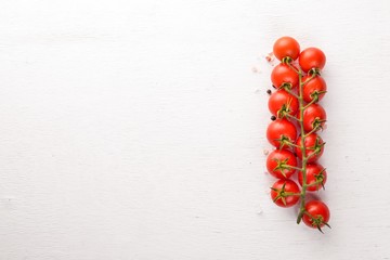 Cherry tomatoes on a twig on a wooden background. Top view.