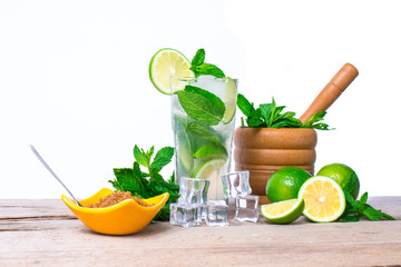 Mojito cocktail with fresh lime, mint leaves and ice cubes in a transparent glass on a wooden background. Refreshing alcohol drink. Isolated on white background.
