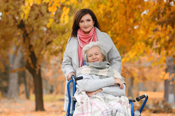 Disabled senior woman and young caregiver in park