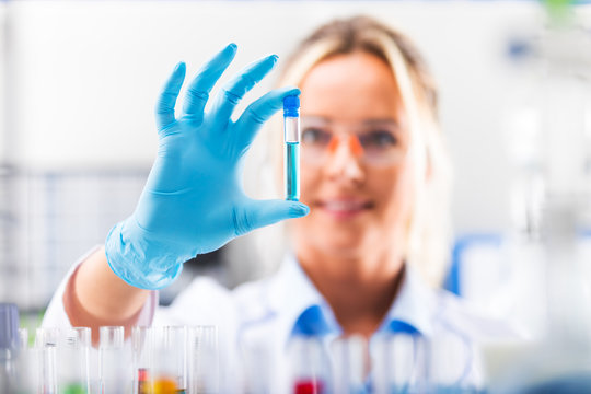 Young attractive female scientist examining test tube with substance probe