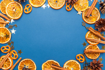 Slices of dried orange, cinnamon and pine cones on the dark background.