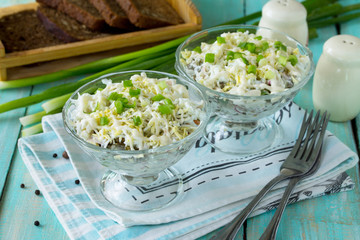 Homemade snacks on the festive table. Salad with squid, radish, sea cabbage, rice and egg.