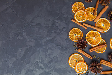 Slices of dried orange, cinnamon and pine cones on the dark background. - 183227616