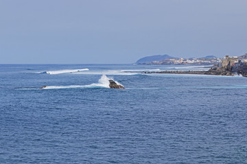 Waves break on small rocks in the middle of the bay.