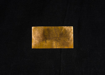 Aged copper plate on black cloth, old worn metal background.