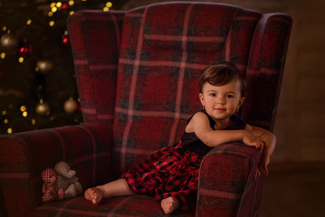 happy little girl sitting near a chrismas tree laughing waiting for presents 
