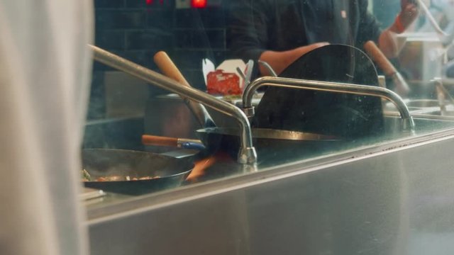 View of cooks's hands preparing chinese food in wok in restaurant in boqueria market