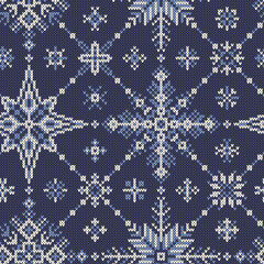 Seamless knitted pattern from white-blue snowflakes