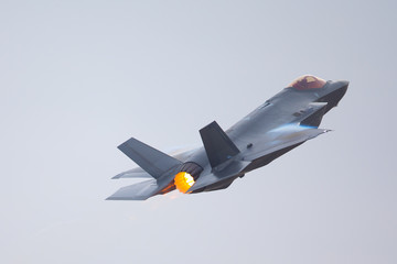 F-35 Lightning II in a high-G maneuver, with afterburner on and condensation trails at the wing’s...
