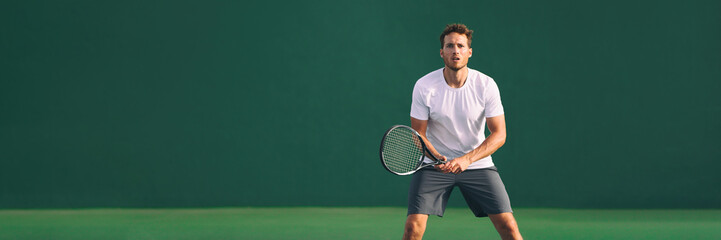 Tennis player man focused in ready position. A male athlete waiting for serve on panoramic green background banner. Challenge and concentration in competition.