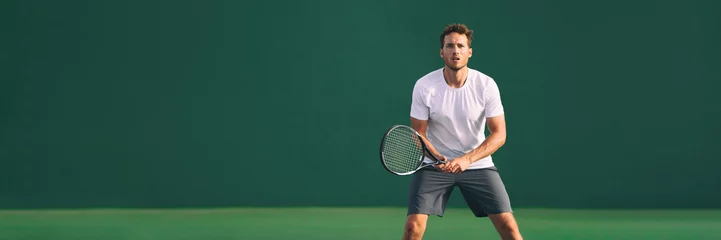  Tennis player man focused in ready position. A male athlete waiting for serve on panoramic green background banner. Challenge and concentration in competition. © Maridav