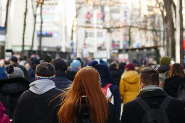 A red haired girl walking down the crowded street