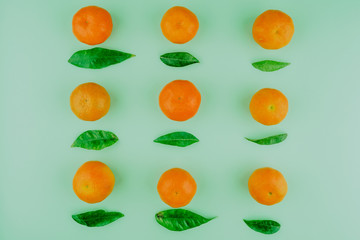 Fresh mandarines with leaves on green background. Top view