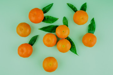 Fresh mandarines with leaves on green background. Top view