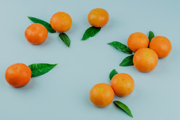 Fresh mandarines with leaves on violet background. Top view