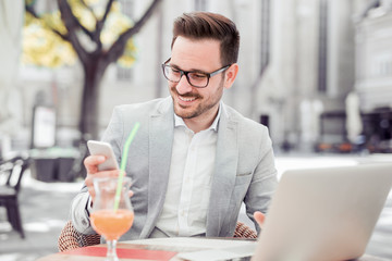 Businessman texting on mobile phone outdoor in the city