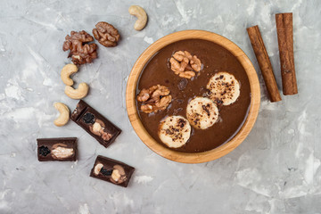 Chocolate smoothie with banana and nuts on grey stone  background, top view