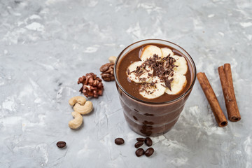 Chocolate smoothie with banana and nuts on grey stone  background