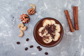 Chocolate smoothie with banana and nuts on grey stone  background, top view