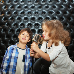 Singing little children with a microphone on a rack
