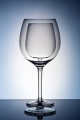 Two empty wineglass for red wine on diffusion lit background in abstract .. composition with reflection
