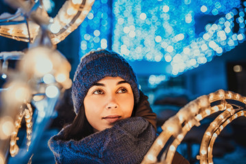 Pretty girl outdoor in cold weather with christmas lights behind